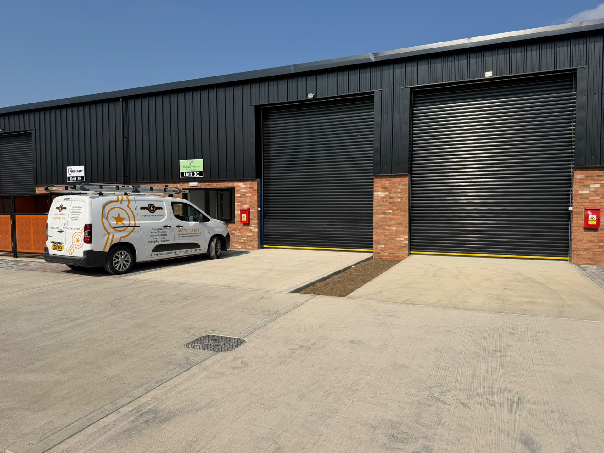 Two large industrial roller shutter doors installed on a commercial unit