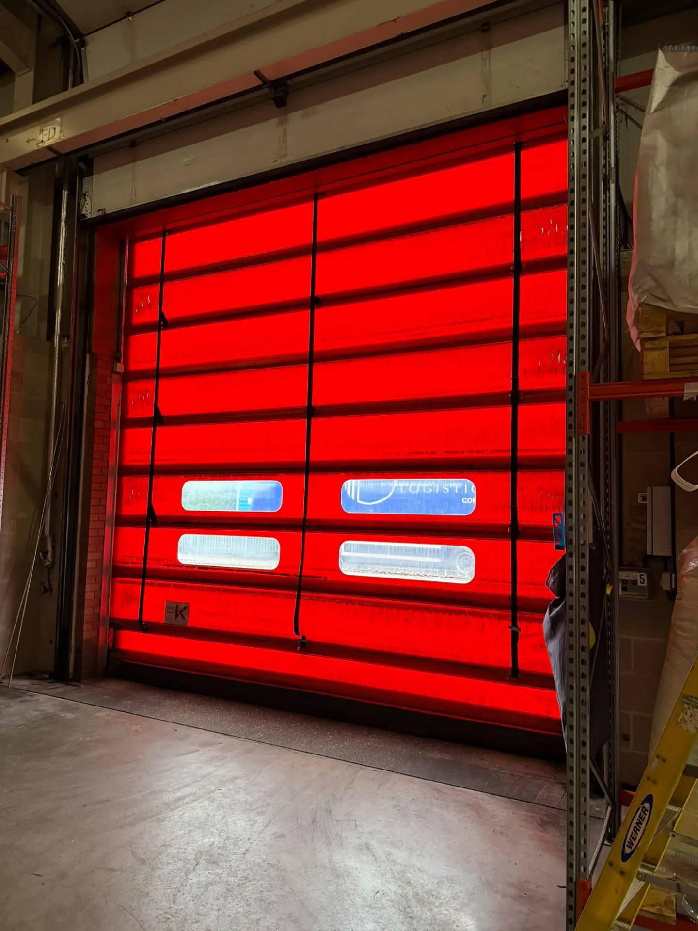Red high speed industrial door installed in a logistics warehouse opening
