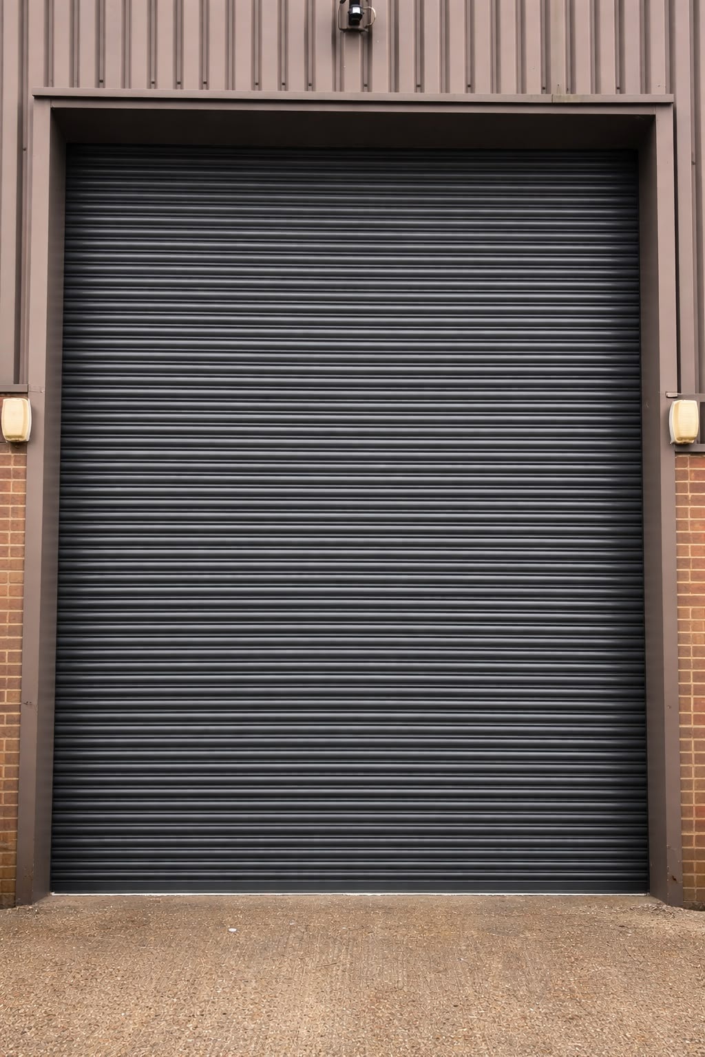 Dark grey industrial roller shutter door in a brick building