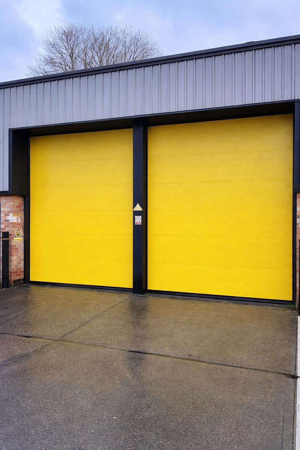 Yellow insulated sectional overhead doors installed on an industrial unit
