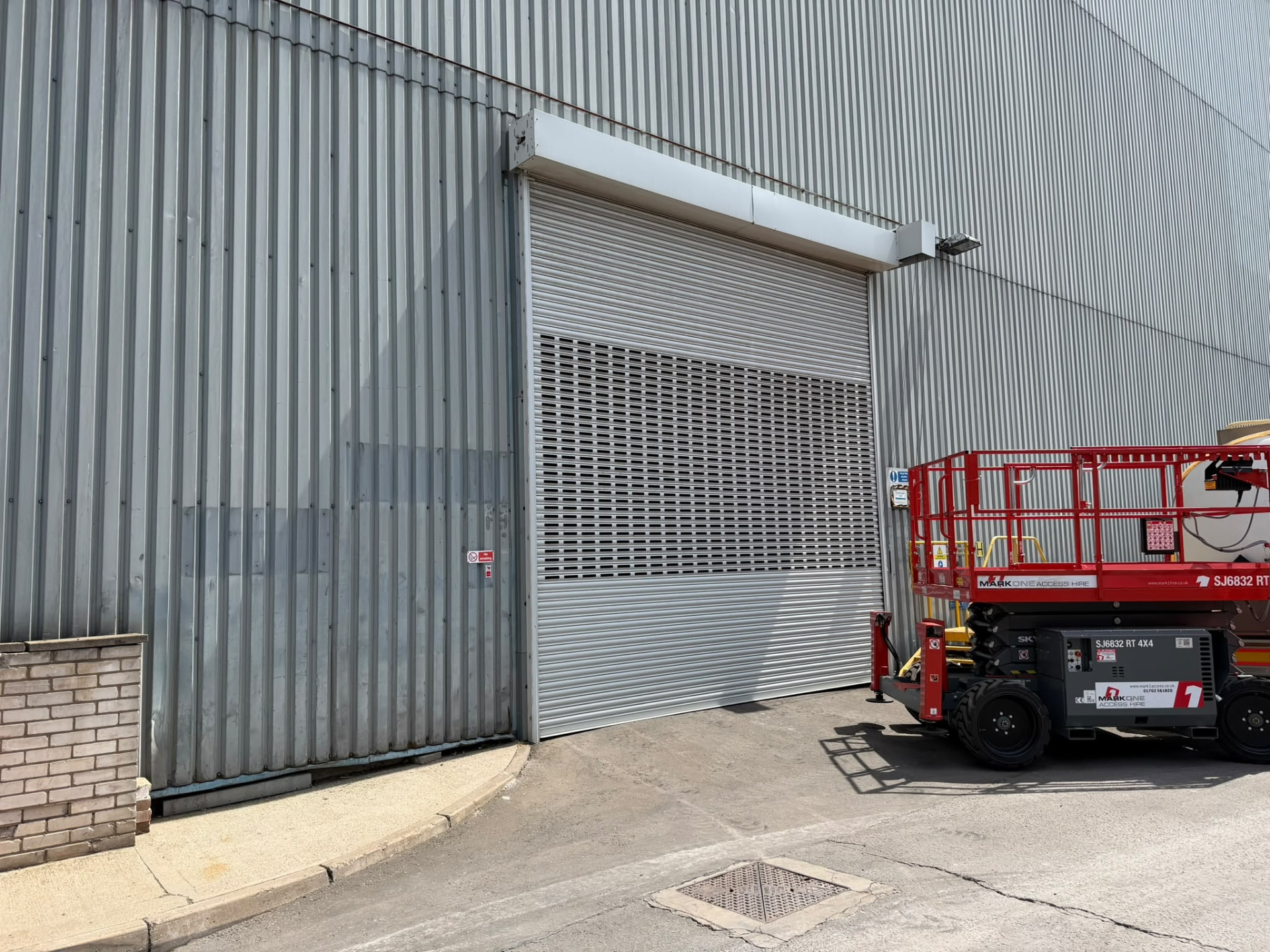 Perforated industrial roller shutter installed using an access platform